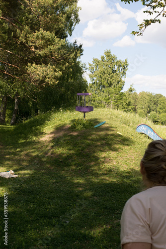 Girl throwing disc golf against basket