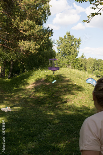 Girl throwing disc golf against basket