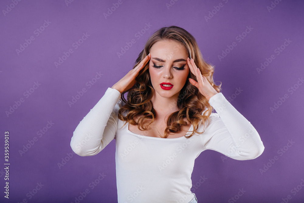 Naklejka premium A young beautiful girl shows emotions and smiles in the Studio on a purple background. Girls for advertising