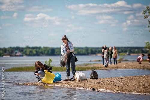 girls with trash on the beach. girls collect garbage on the beach. environmental concern