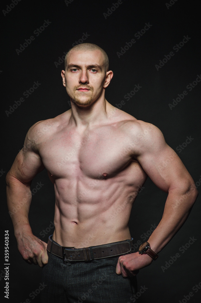 Fototapeta premium Sporty sexy man stands Topless on a dark background. Sports, beauty