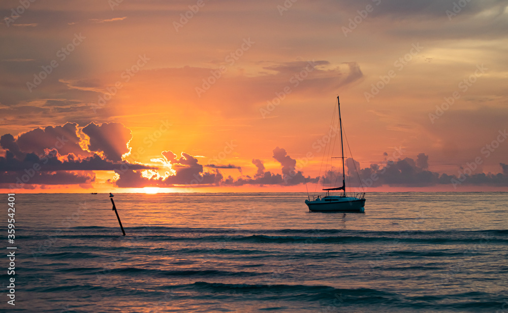 Fototapeta premium Sailing boat moored close to the beach with the sunset as background