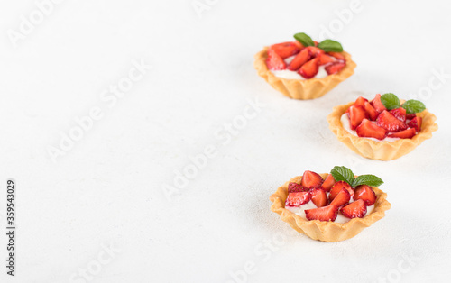 Dessert tartlets with vanilla cream and strawberries on a light background copy space
