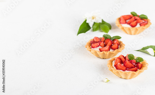 Dessert tartlets with vanilla cream and strawberries on a white background copy space