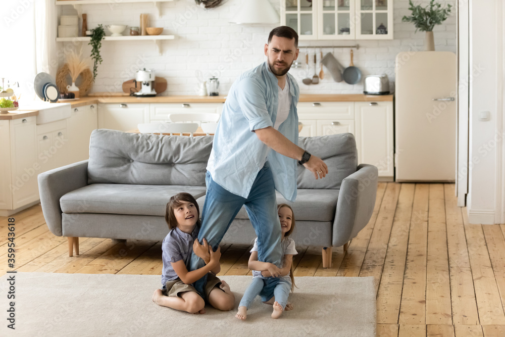 Hyperactive kids holding tired upset father legs when they want to relax. Frustrating dad stressful feels heaviness and headache at home. Fatigue man does n't not want to play with son and daughter. Hyperactive kids holding tired upset father legs when they want to relax. Frustrating dad stressful feels heaviness and headache at home. Fatigue man does n't not want to play with son and daughter.