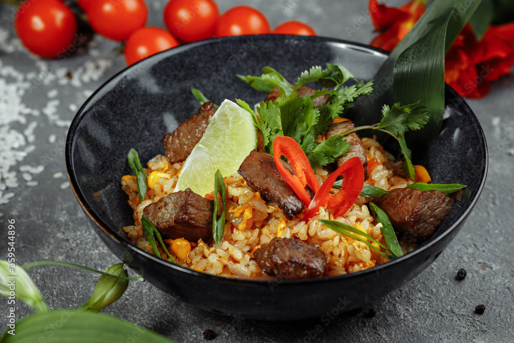 Fried rice with beef and vegetables on a gray textured background Fried rice with beef and vegetables on a gray textured background