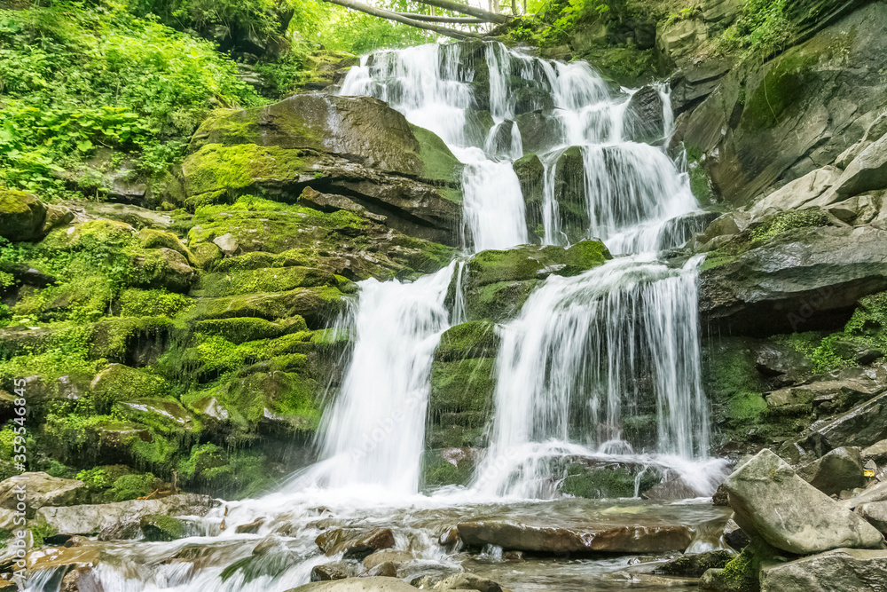 Fototapeta premium Waterfall falling from a high cliff in the mountains.