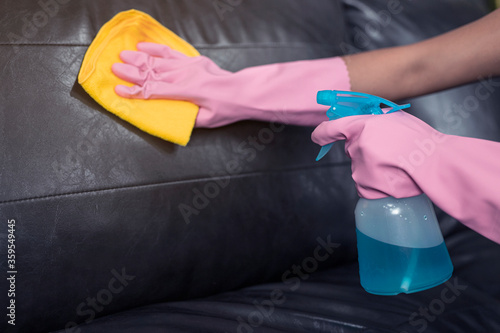 Woman wipe sofa with germicidal spray and wipe with towel.