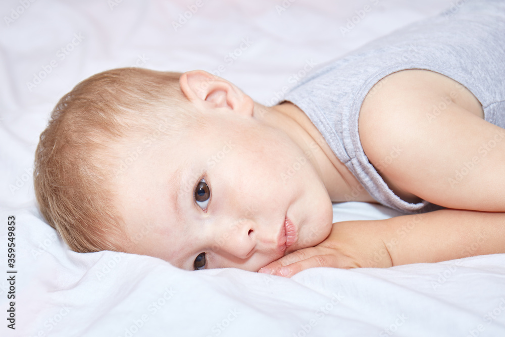 Toddler thought lying on a white bedspread Toddler thought lying on a white bedspread