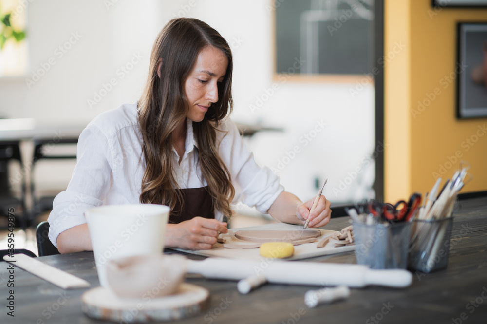 Woman's fingers adding and adjusting a clay part on a future ceramic product. Woman's fingers adding and adjusting a clay part on a future ceramic product.