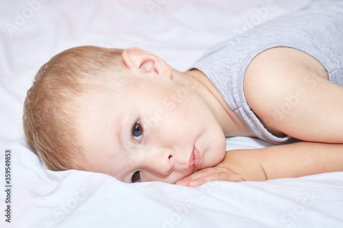 Toddler thought lying on a white bedspread