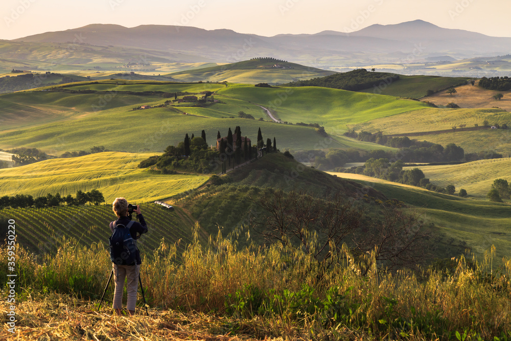 Photographing at sunrise beautiful Tuscany landscape with traditional farm house, hills and meadow. Val d'orcia, Italy.