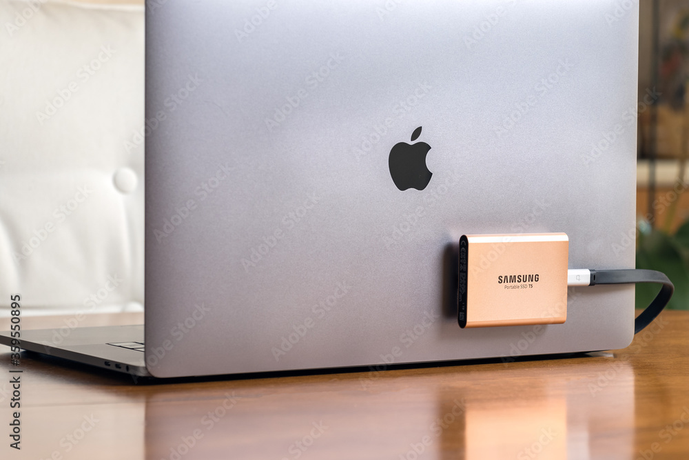 A Samsung T5 Portable SSD hard drive connected to a Macbook Pro secured  with velcro tape. Stock Photo | Adobe Stock