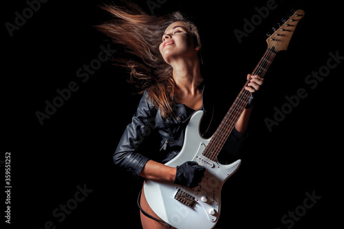 Sexy woman in leather jacket and gloves playing guitar