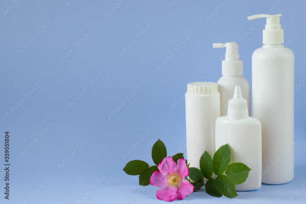 Jar with baby powder, bottle of talcum powder, liquid soap and shower gel isolated on a blue background with a rose. Jar with baby powder, bottle of talcum powder, liquid soap and shower gel isolated on a blue background with a rose.
