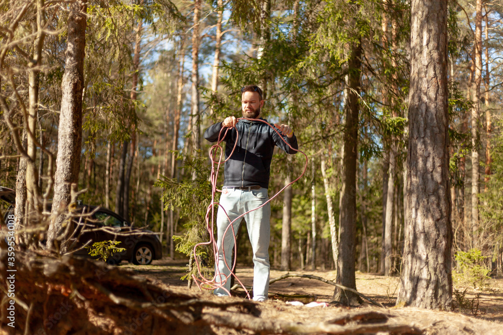 young man with a rope in his hands stands in the forest young man with a rope in his hands stands in the forest