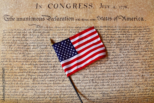 Declaration of Independence with a modern American flag laying on top of the parchment.