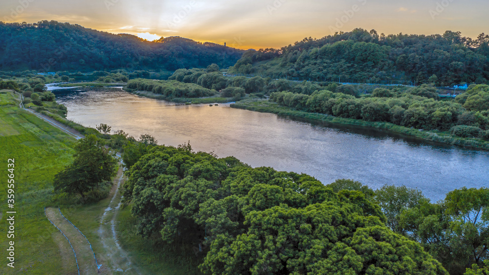 Aerial landscape of river with sun setting behind mountains.