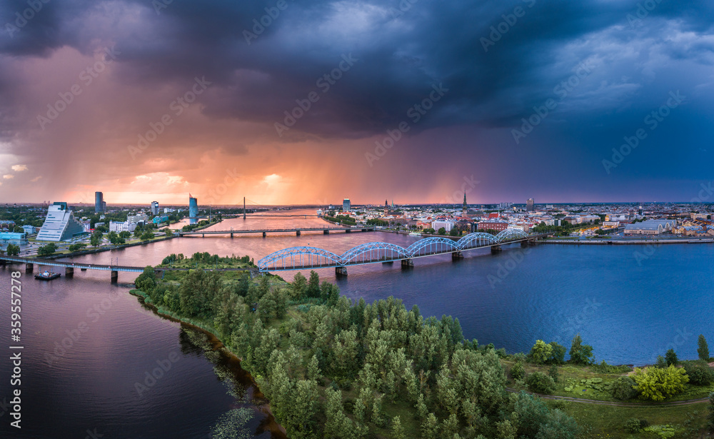 Aerial view of iconic Riga city downtown in dramatic sunset. Modern architecture in rainy weather with storm clouds in warm colors. 
