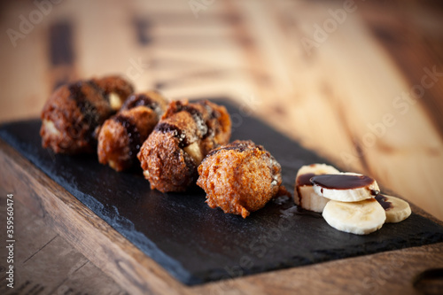 Bananas in a batter on a slate stone with a wooden tray