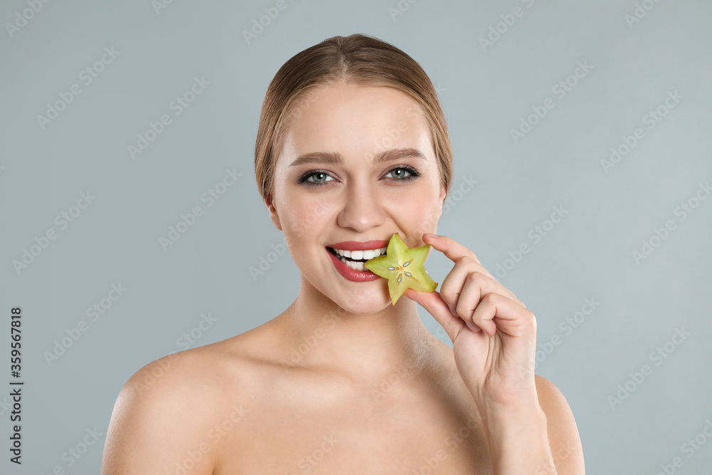 Young woman with slice of carambola on grey background. Vitamin rich food Young woman with slice of carambola on grey background. Vitamin rich food