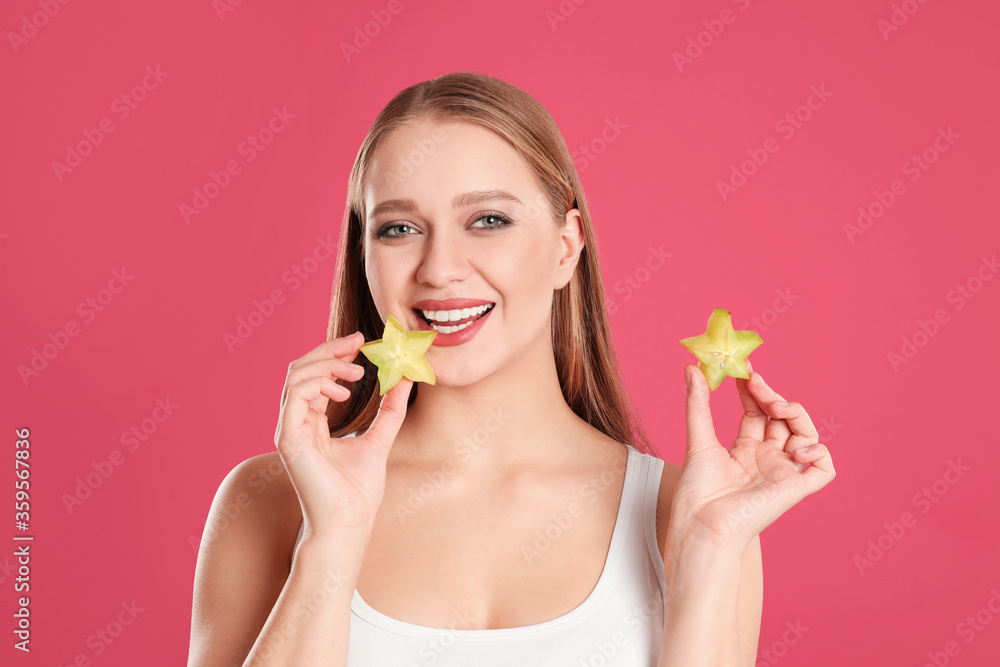 Young woman with cut carambola on pink background. Vitamin rich food Young woman with cut carambola on pink background. Vitamin rich food