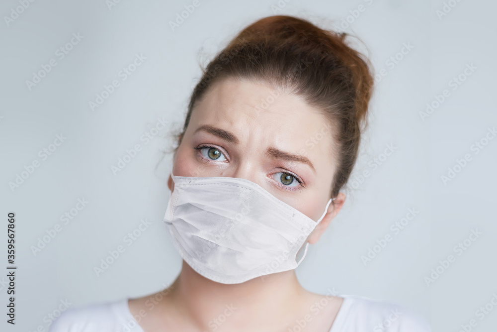 Young girl in a protective mask during the epidemic of coronavirus on a gray background.