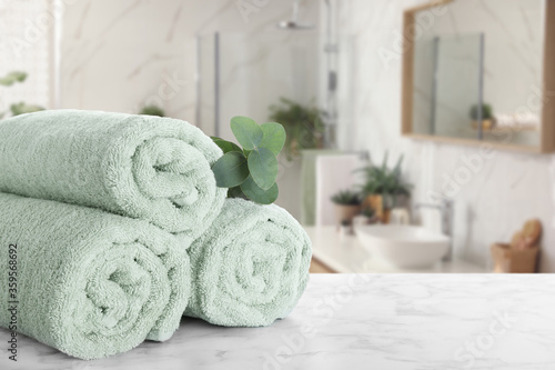 Fresh towels and eucalyptus branch on marble table in bathroom. Space for text