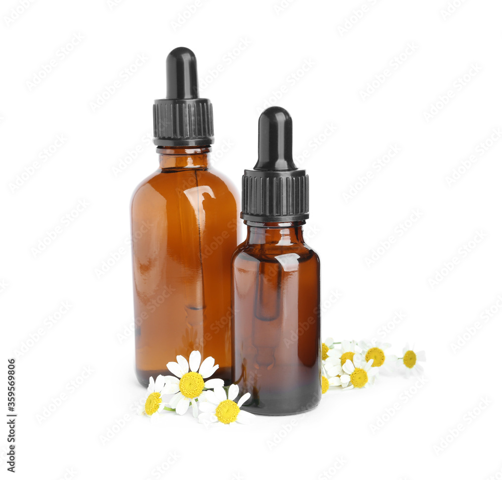 Bottles of essential oil and fresh chamomiles isolated on white Bottles of essential oil and fresh chamomiles isolated on white