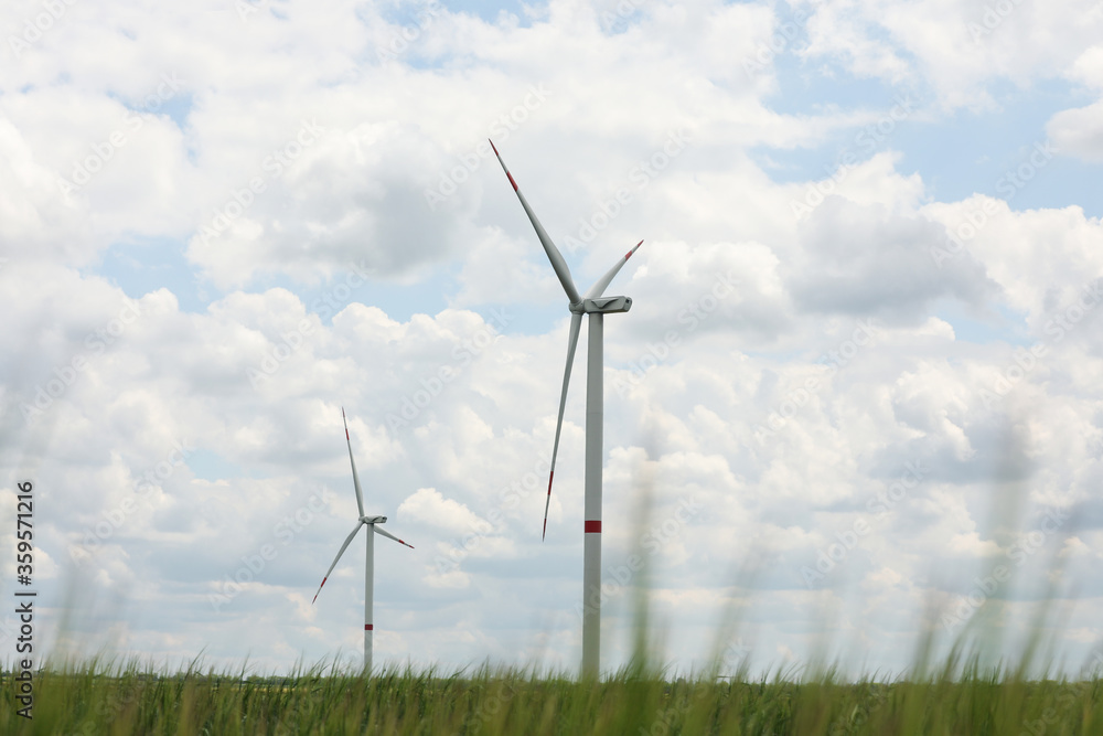 Modern wind turbines in field on cloudy day. Alternative energy source Modern wind turbines in field on cloudy day. Alternative energy source