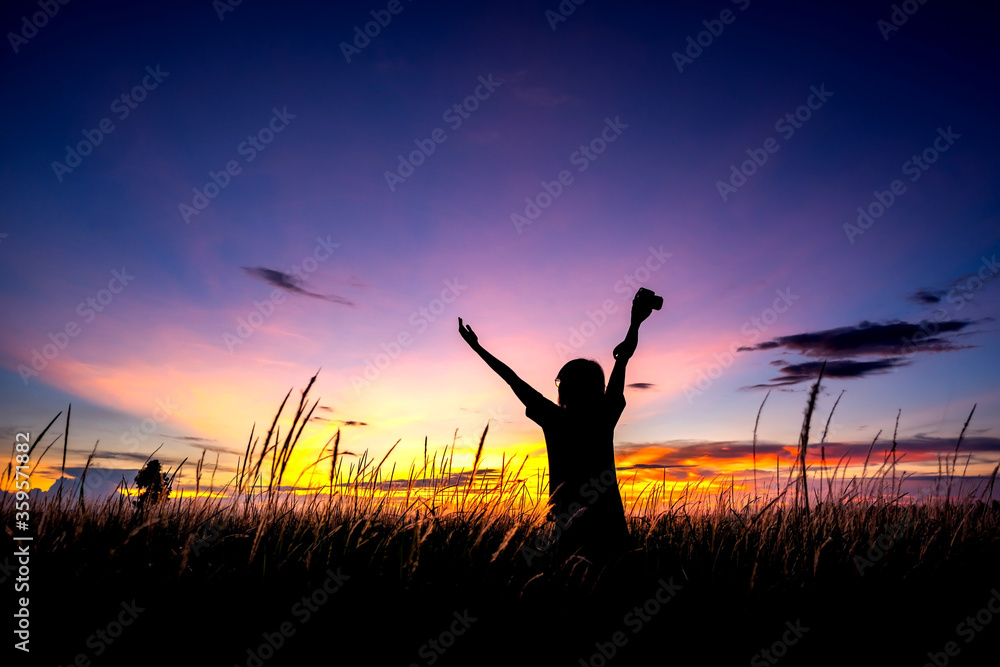 Silhouette of the woman standing and showing hands lonely at the field during beautiful sunset