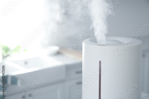 Modern air humidifier in kitchen, closeup. Space for text
