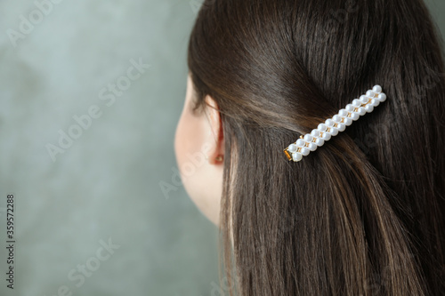 Young woman with beautiful hair clip on grey background, closeup