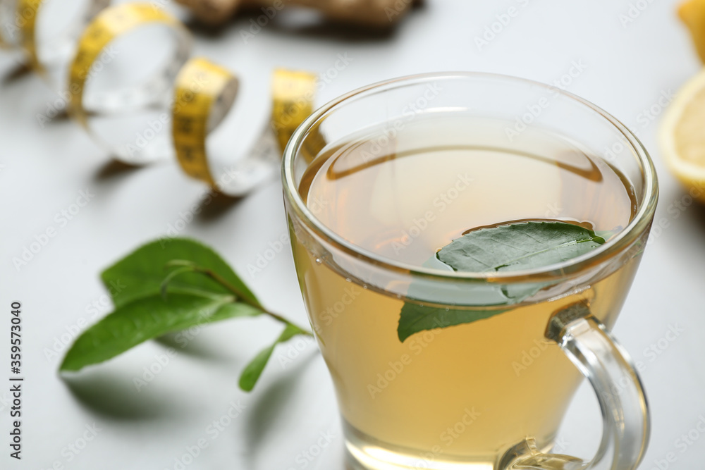 Herbal diet tea and measuring tape on light table, closeup Herbal diet tea and measuring tape on light table, closeup