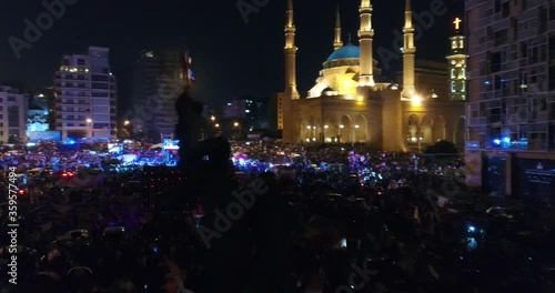 Beirut, Lebanon 2019 : night drone shot passing by martyr monument statue in Martyr square, during the Lebanese revolution, with thousands of protesters revolting against government failure  photo