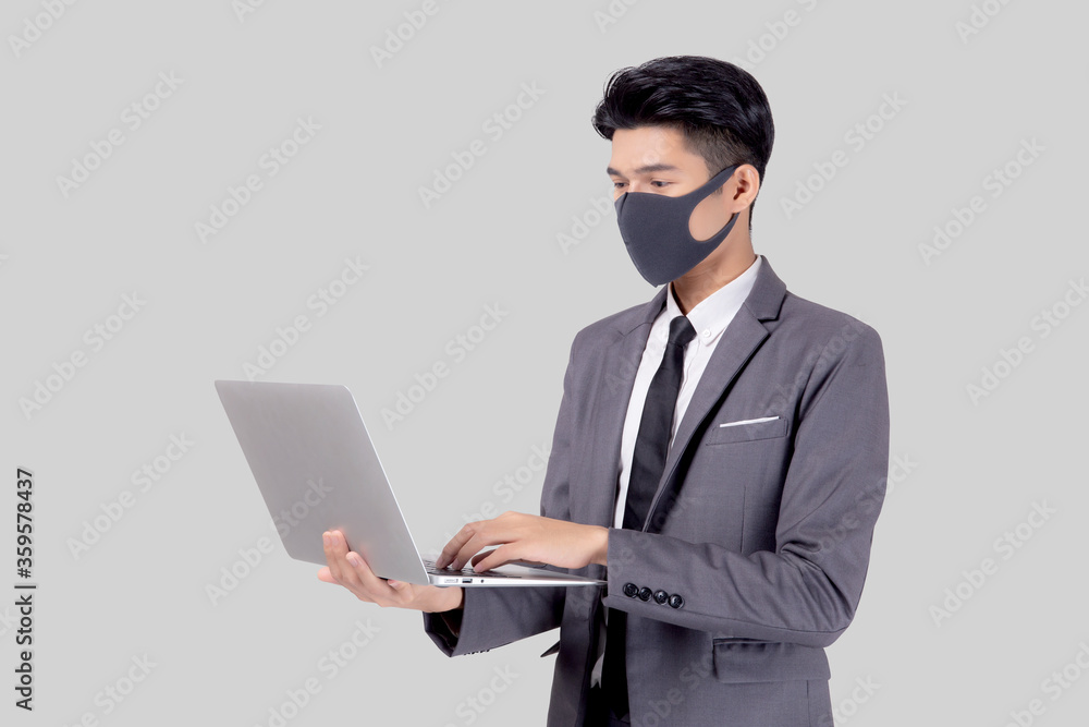 Young asian business man in face mask work laptop computer isolated. Young asian business man in face mask work laptop computer isolated.