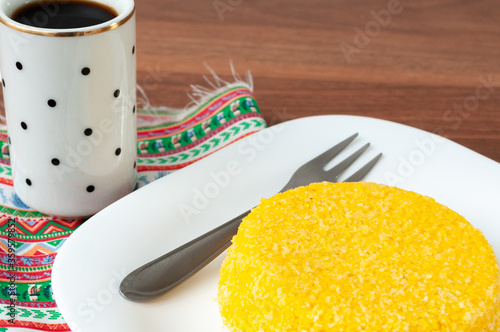 tasteful and colorful brazilian corn couscous served with a cup of coffee on a wooden table photo