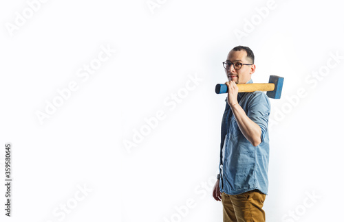 A man in blue shirt holding a big hammer on his shoulder and smiling