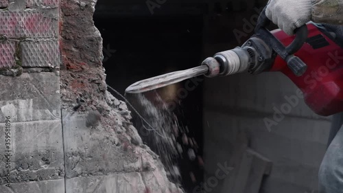 Close-up. Worker breaks the wall with a perforator. Slow motion. photo