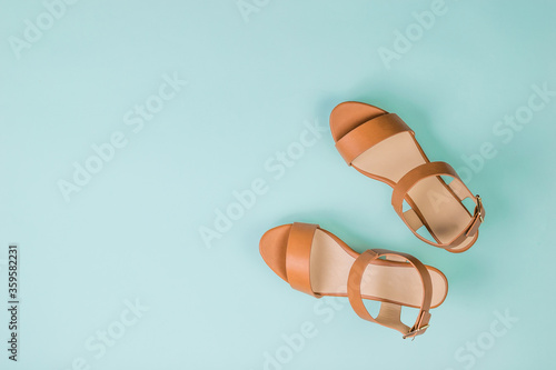 Women's leather stylish sandals on a light blue background. Flat lay.