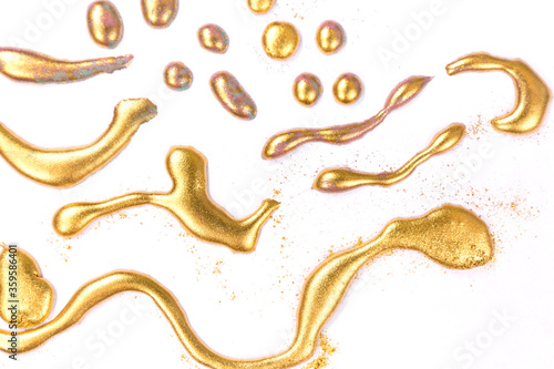 Golden ink drops on white paper background.
