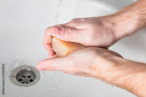Man use soap and washing hands under the water tap. Hygiene concept hand detail.