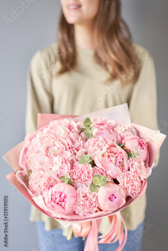 Bouquet of pink peonies and carnations in womans hands. Modern floral shop. Finished work of the florist. Delivery fresh cut flower from online store