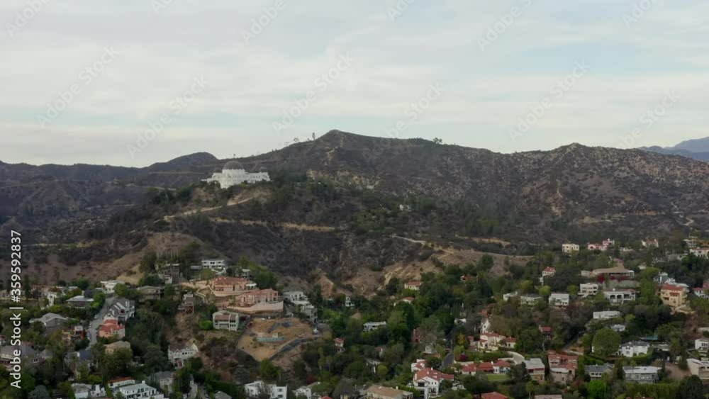 AERIAL: Griffith Observatory far away with view on Hollywood Hills in Daylight, Los Angeles, California, Cloudy AERIAL: Griffith Observatory far away with view on Hollywood Hills in Daylight, Los Angeles, California, Cloudy