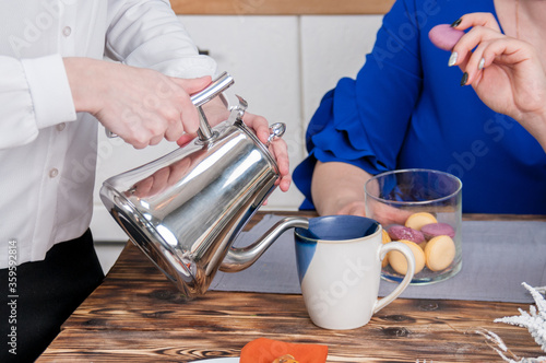 Fototapeta Naklejka Na Ścianę i Meble -  Waitress hands pour coffee to a woman from a teapot into a mug close up