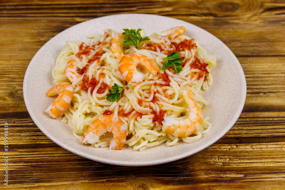 Spaghetti pasta with prawns, tomato sauce and parsley on wooden table