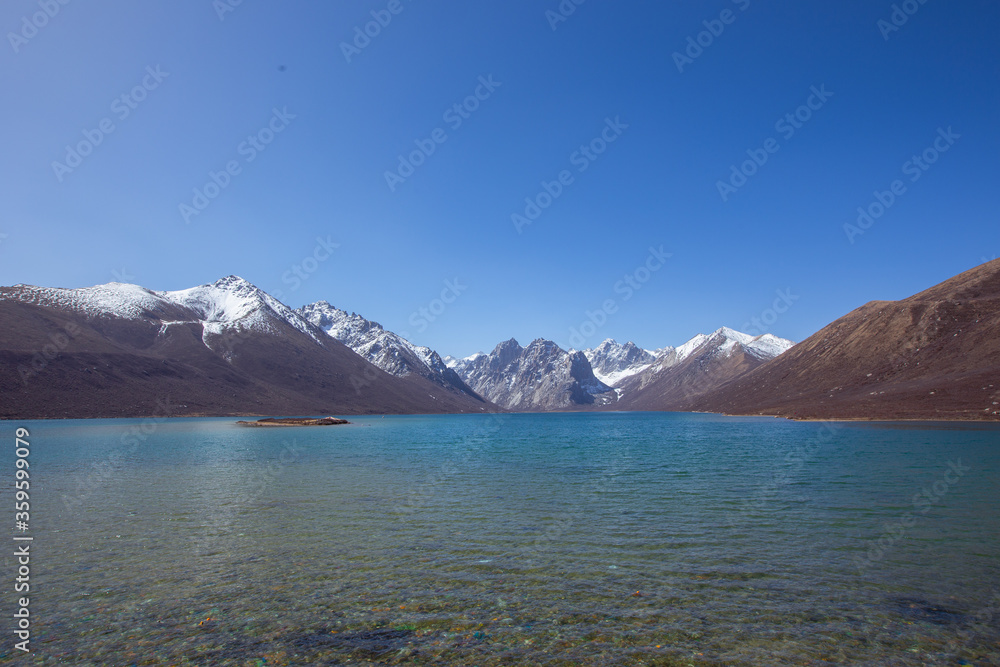 Nianbaoyuze, A sacred lake in Tibet with green water and snow mountains in the back.