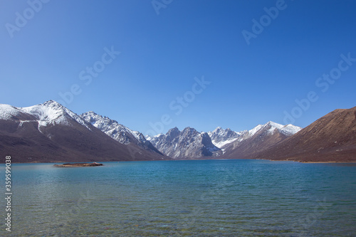 Nianbaoyuze, A sacred lake in Tibet with green water and snow mountains in the back. © Zimu