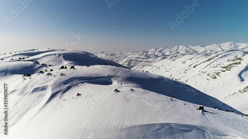 Sensational flight above white snow covered Akoura mountain ridge towards bright blue sky and range, Lebanon, overhead aerial approach