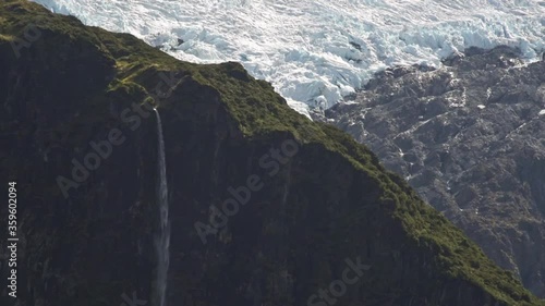 Long waterfall of Bridal Veil Falls falling over a valley with glacial ice in the background. At Mount Aspiring, New zealand, south island. photo